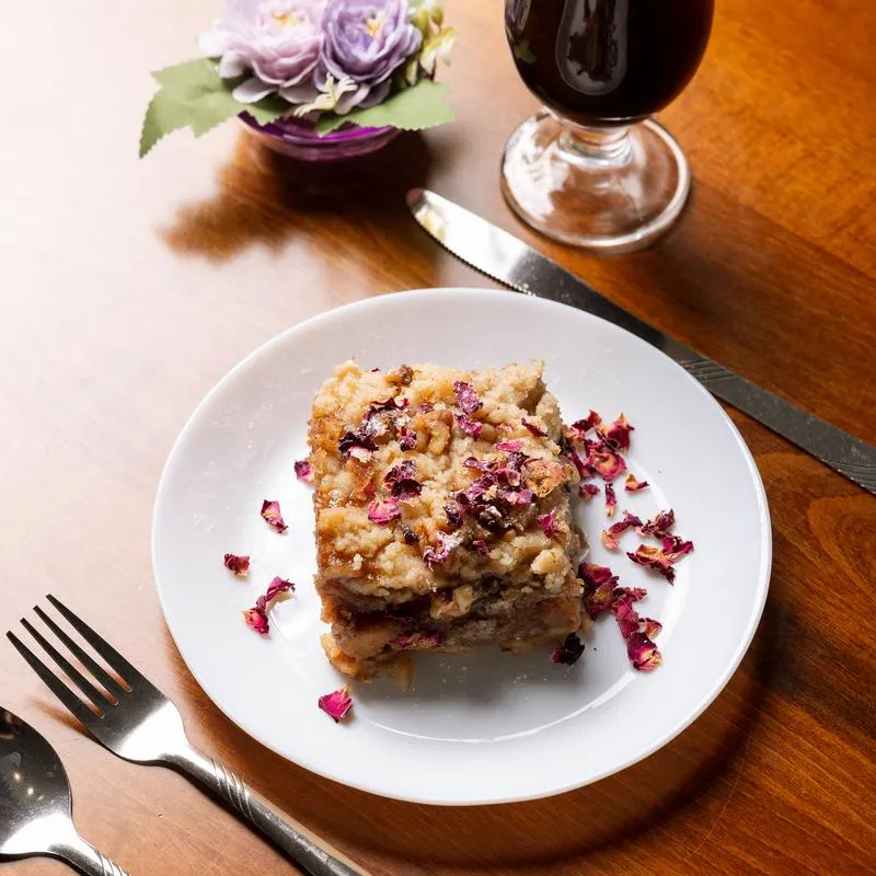 Apple Crumble pie served on the table with cutlery and a cup of coffee.