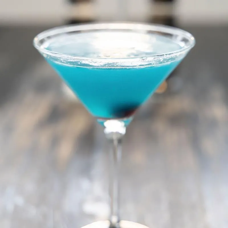 Blue martini cocktail in a stem glass.