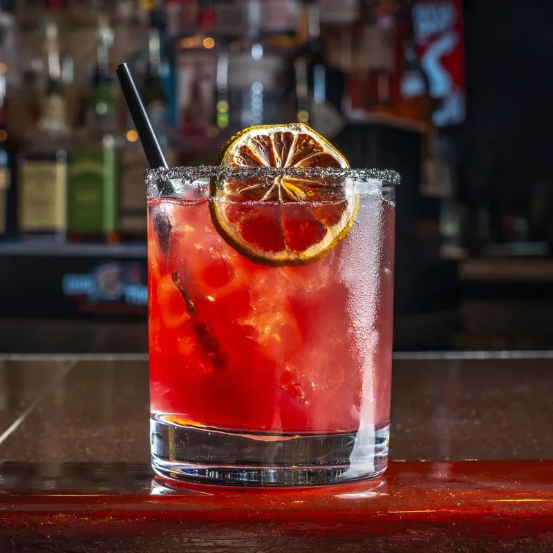 Red Margarita served in a rimmed rocks glass with a dried lime wheel.