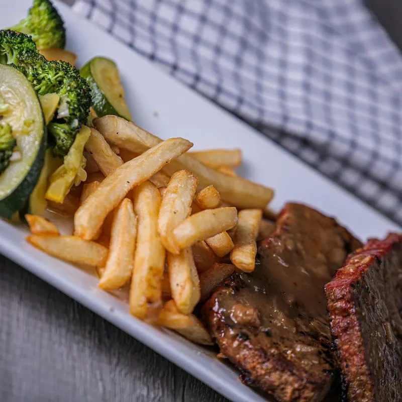 Grilled meat, fries and green vegetables on the side.