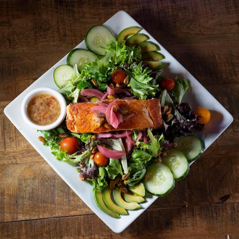 Grilled salmon salad, with mixed greens, tomatoes, avocado, pickled red onion and dressing
