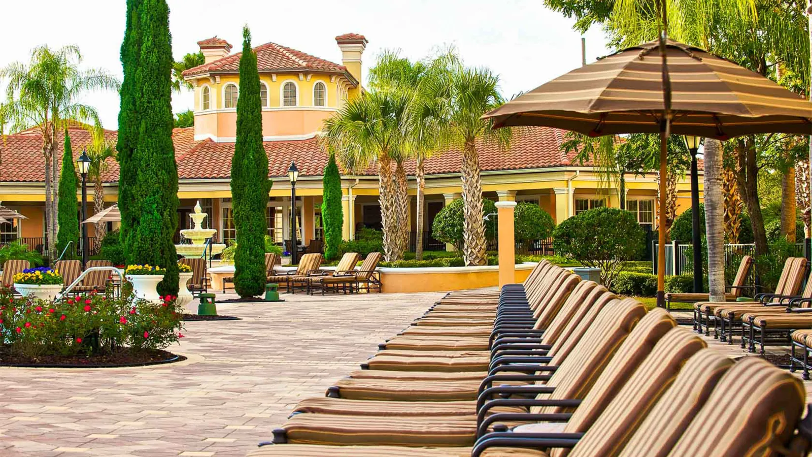 a patio with pool chairs and umbrellas