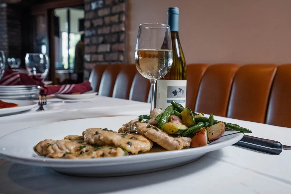 Chicken with green beans and a glass of white wine in the dining room