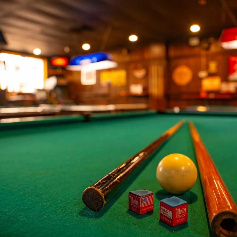 Pool cues, a ball, and chalk on a pool table.
