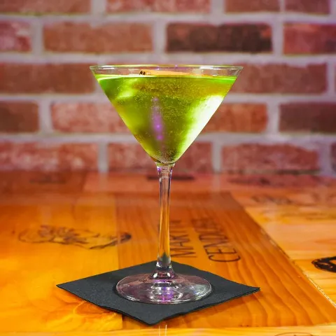 Bright green cocktail served in a martini glass on a wooden table.