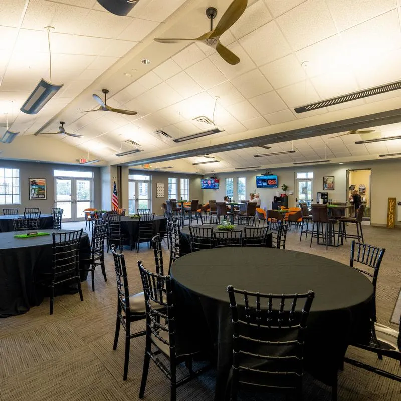 Event space set up for a gathering, featuring round tables with black tablecloths.