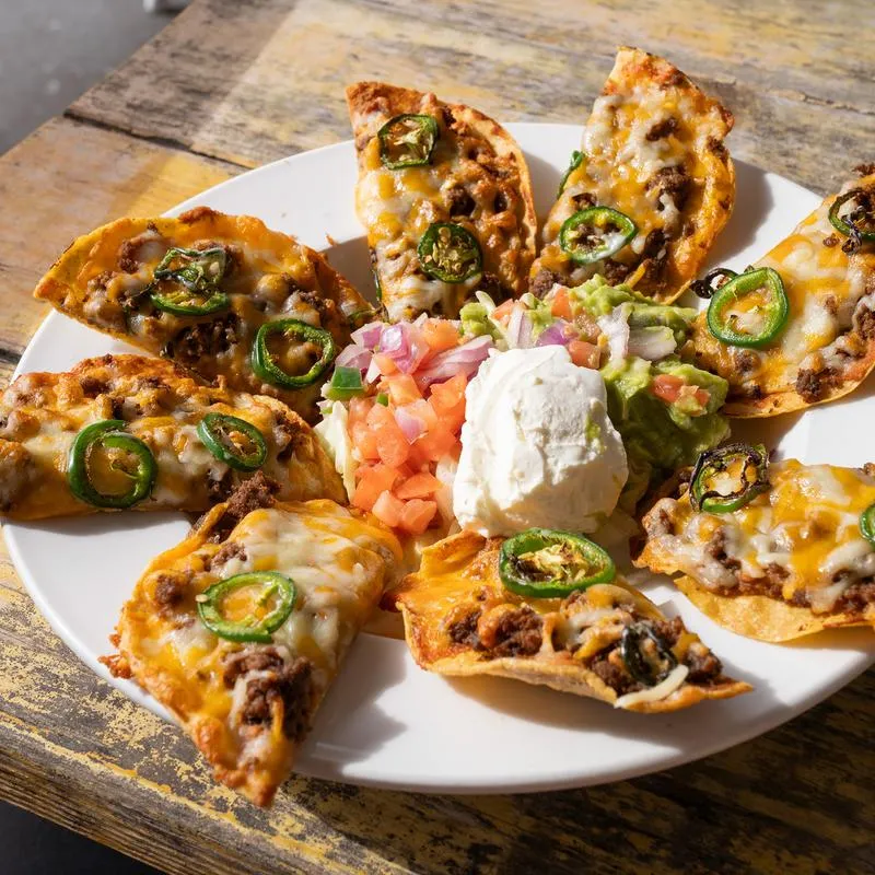 Plate of Tostada Nachos served with guacamole, sour cream, lettuce and pico de gallo.