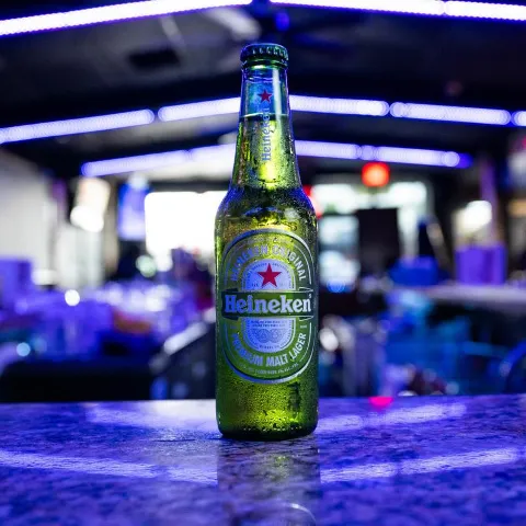 A bottle of European beer on a bar counter with blue neon lights.