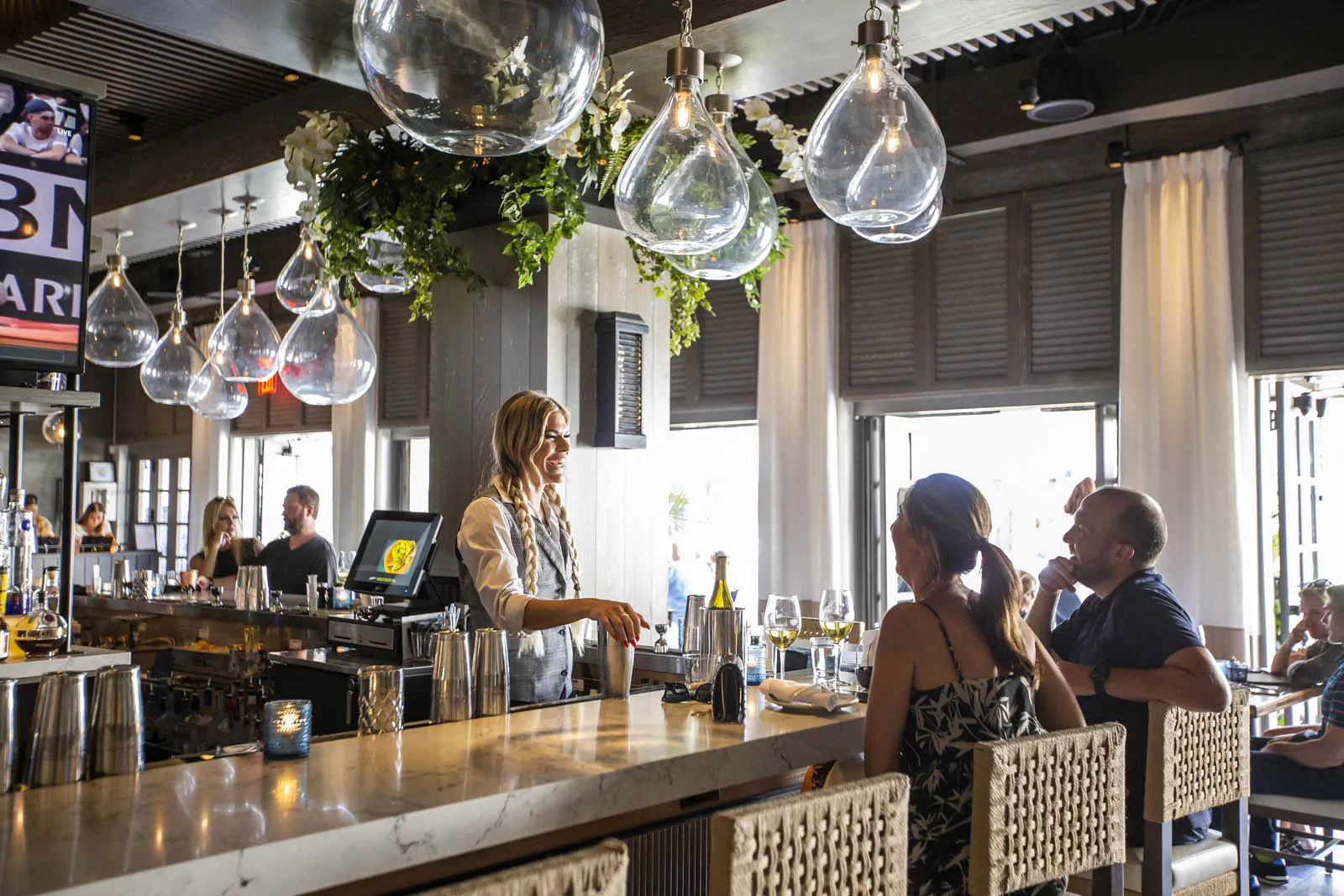 Guests talking with bartender at Del Mar Naples restaurant in Florida.
