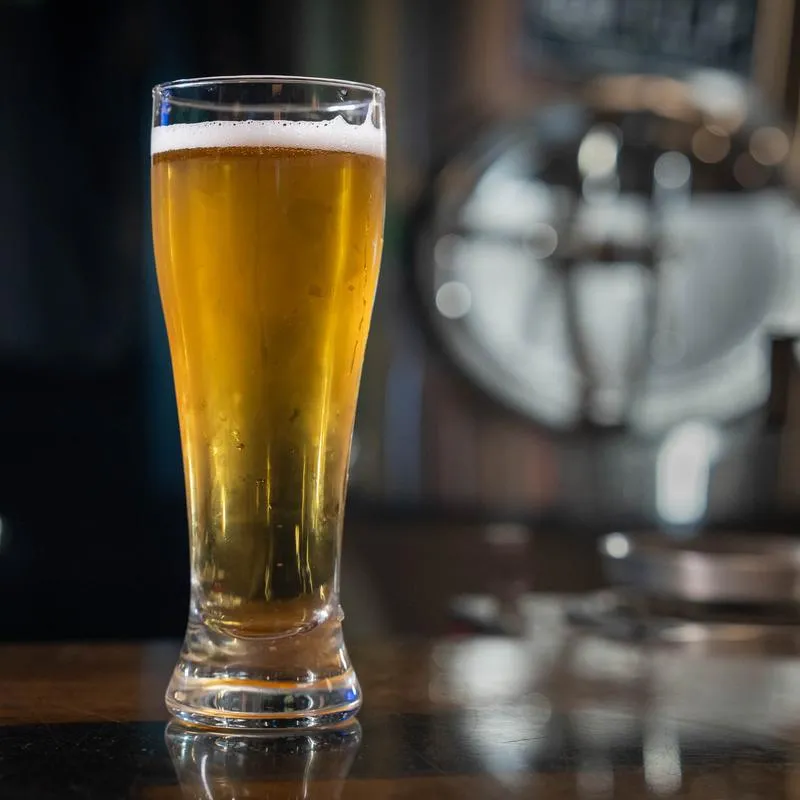 Tall glass of golden beer on a bar counter.
