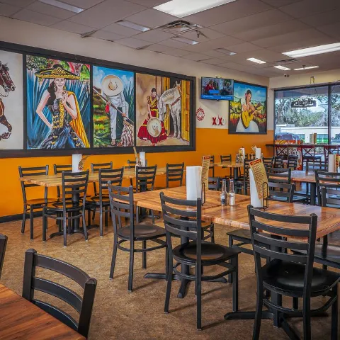 Dining room with tables, chairs and traditiona Mexican artwork on the wall.