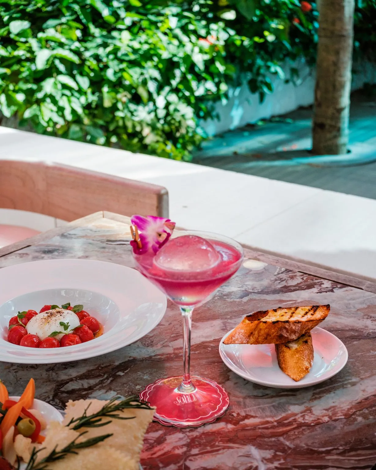 pink cocktail and grilled bread on a marble table outdoors,