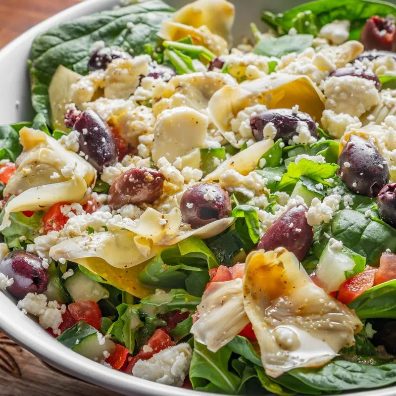 Salad with mixed greens, olives, tomatoes, onions, cucumber, feta, and artichokes.