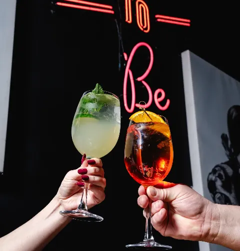 Two people clinking glasses of drinks together