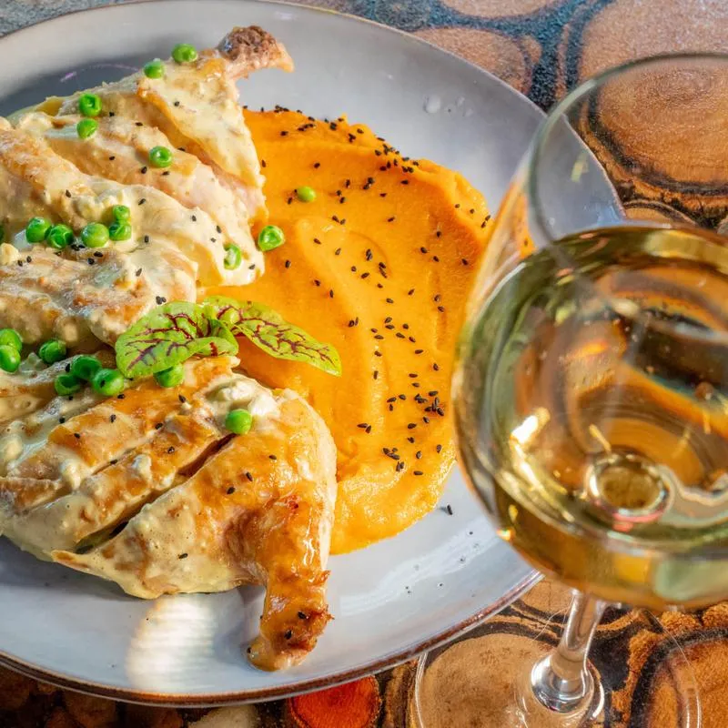 Half Free Range Chicken Veluote, accompanied with a glass of white wine, top view.