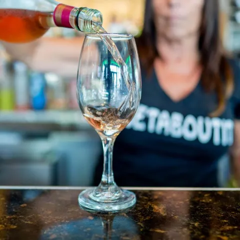 Vine being pured into a glass by stuff member behind the bar.