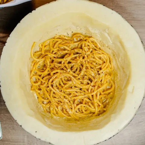 A bowl filled with noodles on top of a wooden table.