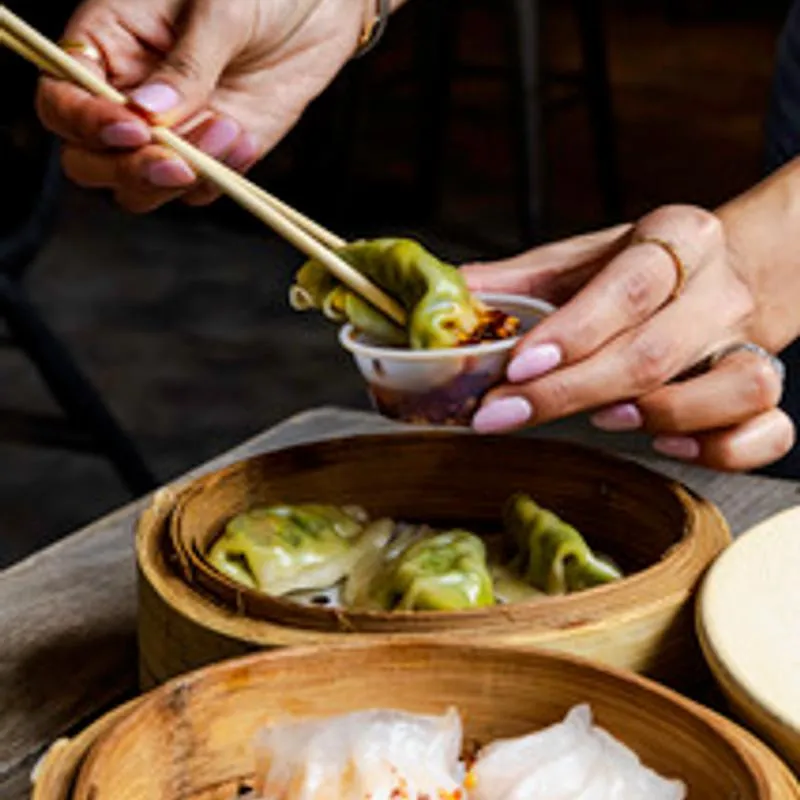 Hands picking up food with chopsticks.