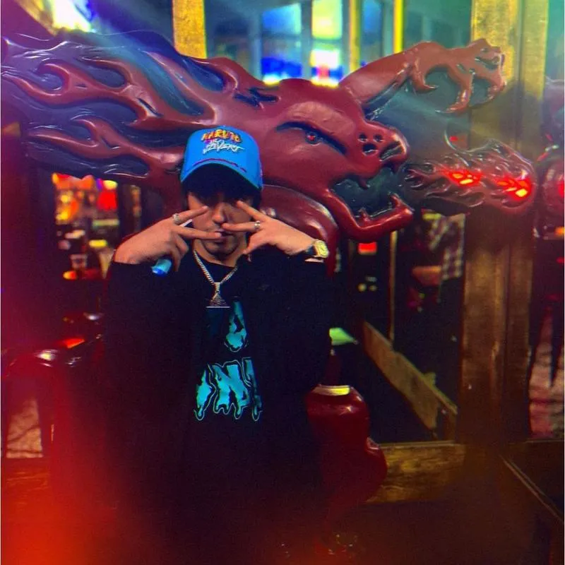 Person posing in front of a dragon sculpture indoors.