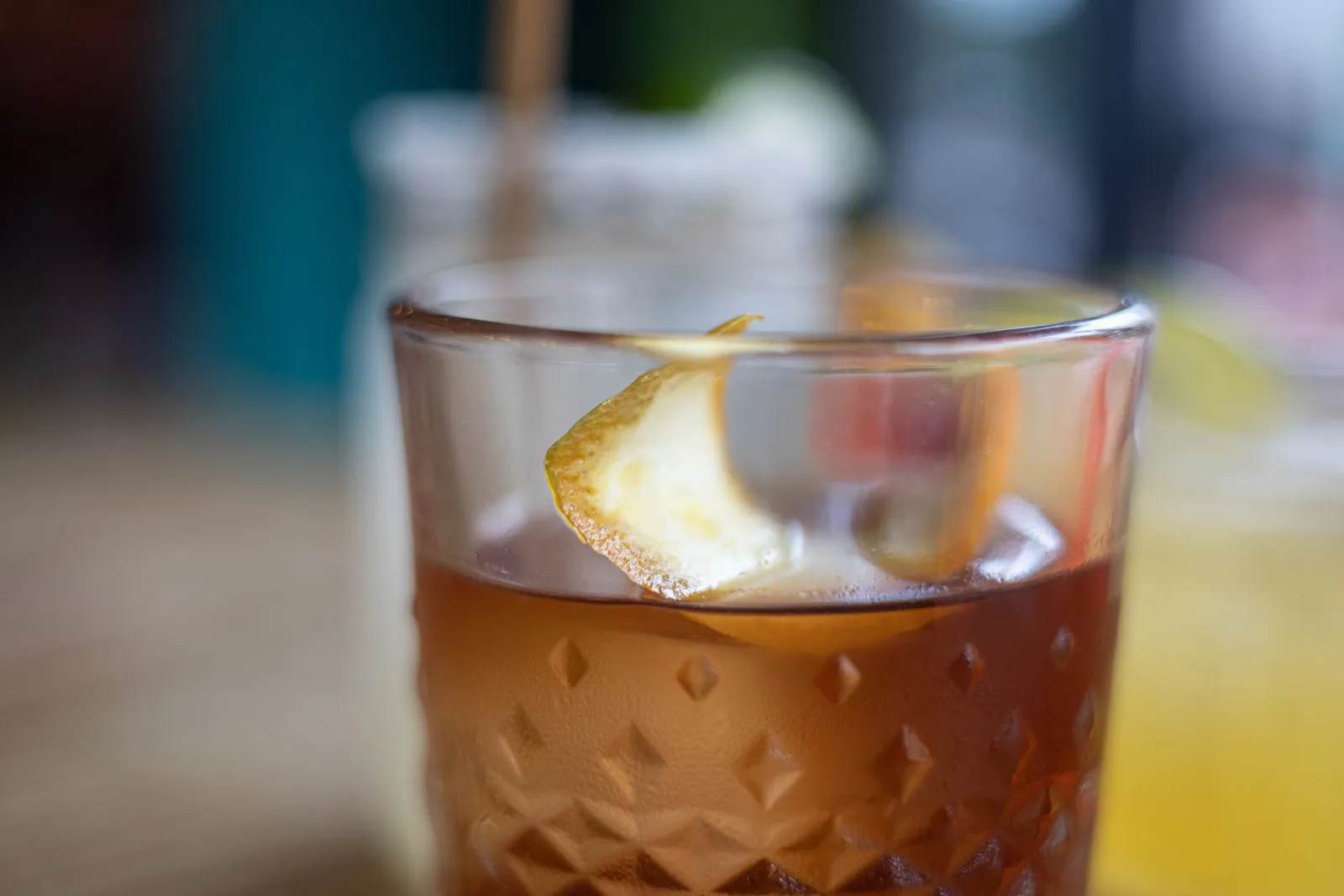 Close-up of a glass of iced dark beverage with a lemon wedge garnish.