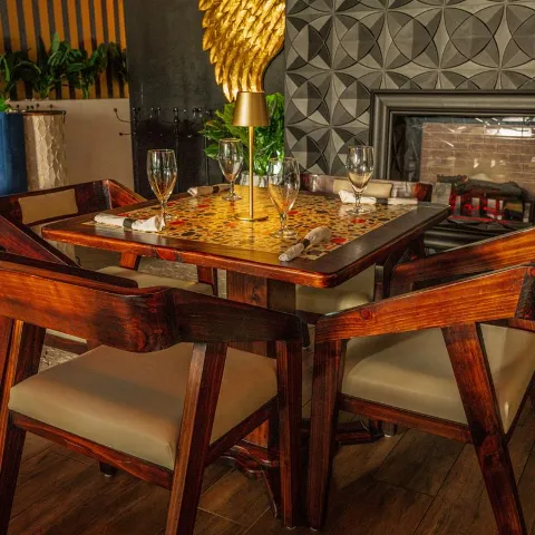 Interior featuring a gold-topped table set for dining and rustic wooden chairs.