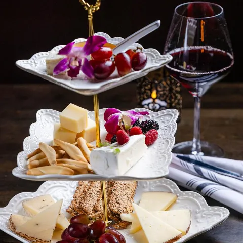 Cheese platter with wine glass in the back.