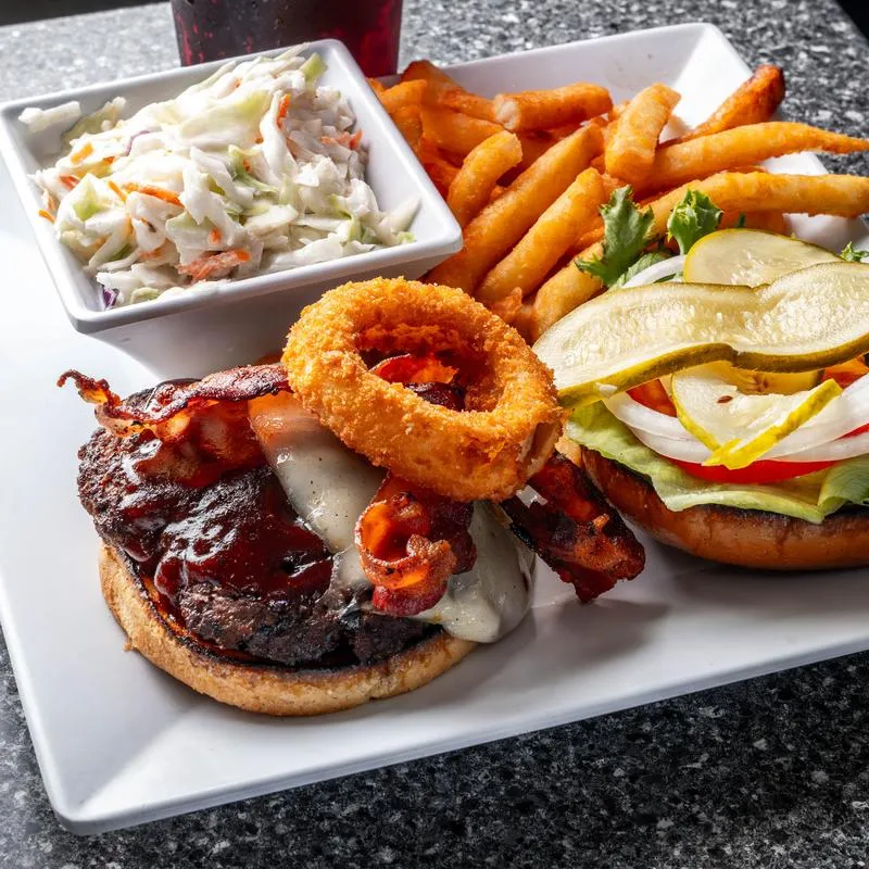 Britt's Burger topped with bacon, BBQ sauce and onion ring, served with fries and coleslaw.