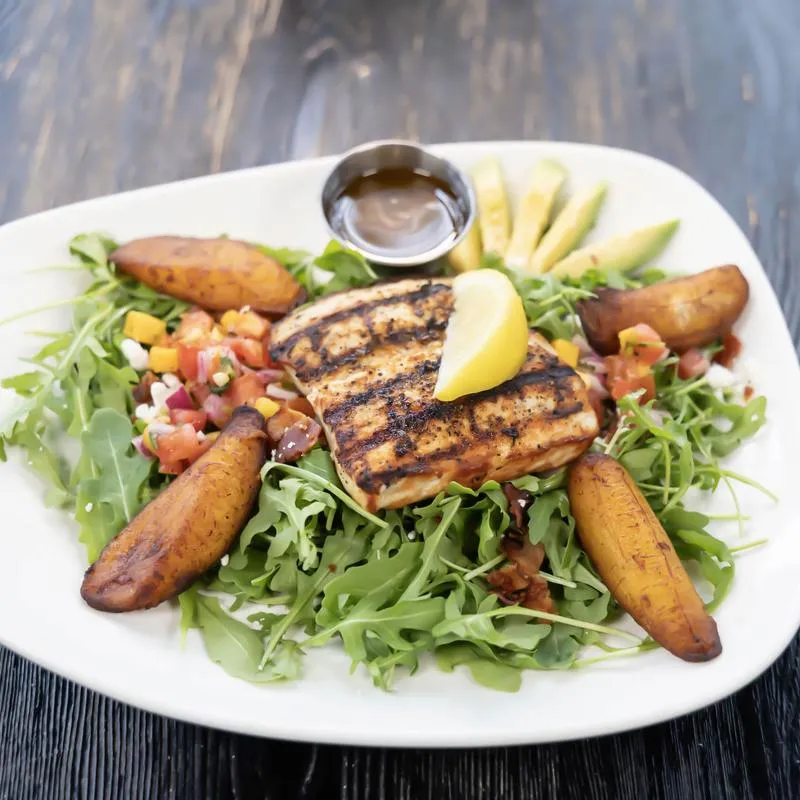 Grilled mahi salad with mixed greens, fried plantains, and sliced avocado.
