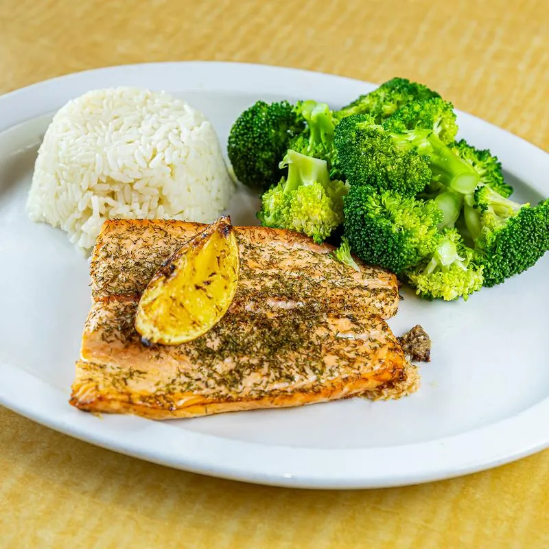 Grilled salmon fillet sauteed in lemon, white wine, honey, and dill, served with rice and broccoli.