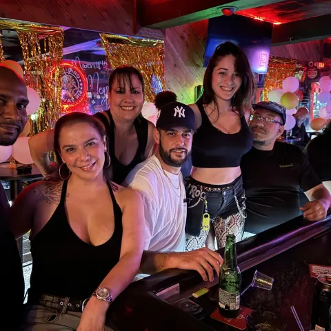 Group of people posing together at a bar counter.
