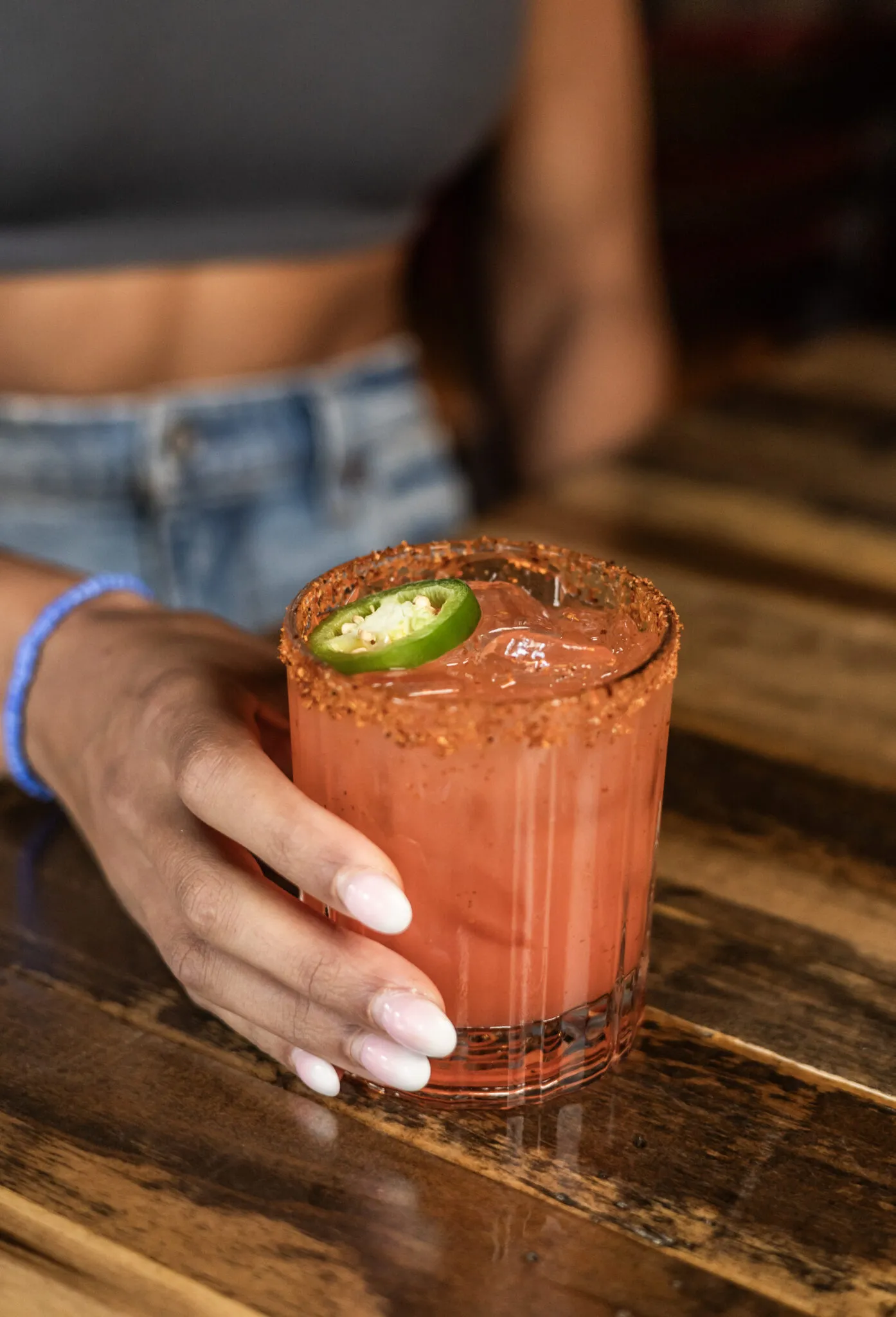 Hand holding spicy jalapeño-rimmed cocktail