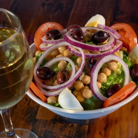 House salad with chickpeas, olives, onions, and tomatoes served with white wine.