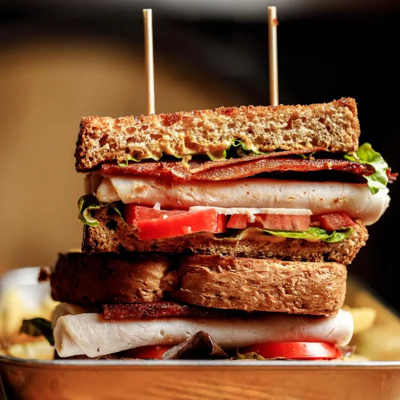 Turkey club sandwich with bacon, tomato, and lettuce.