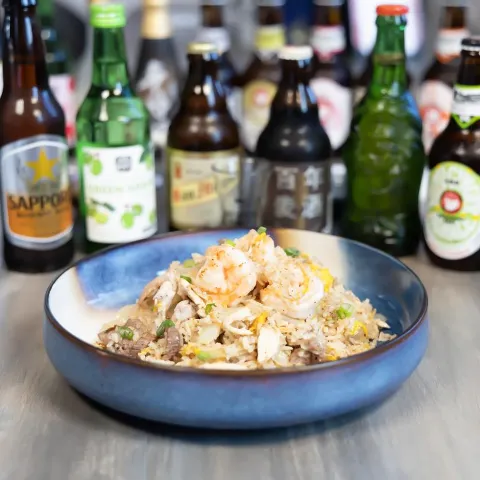 Shrimp fried rice served on the table with various bottles of beer.