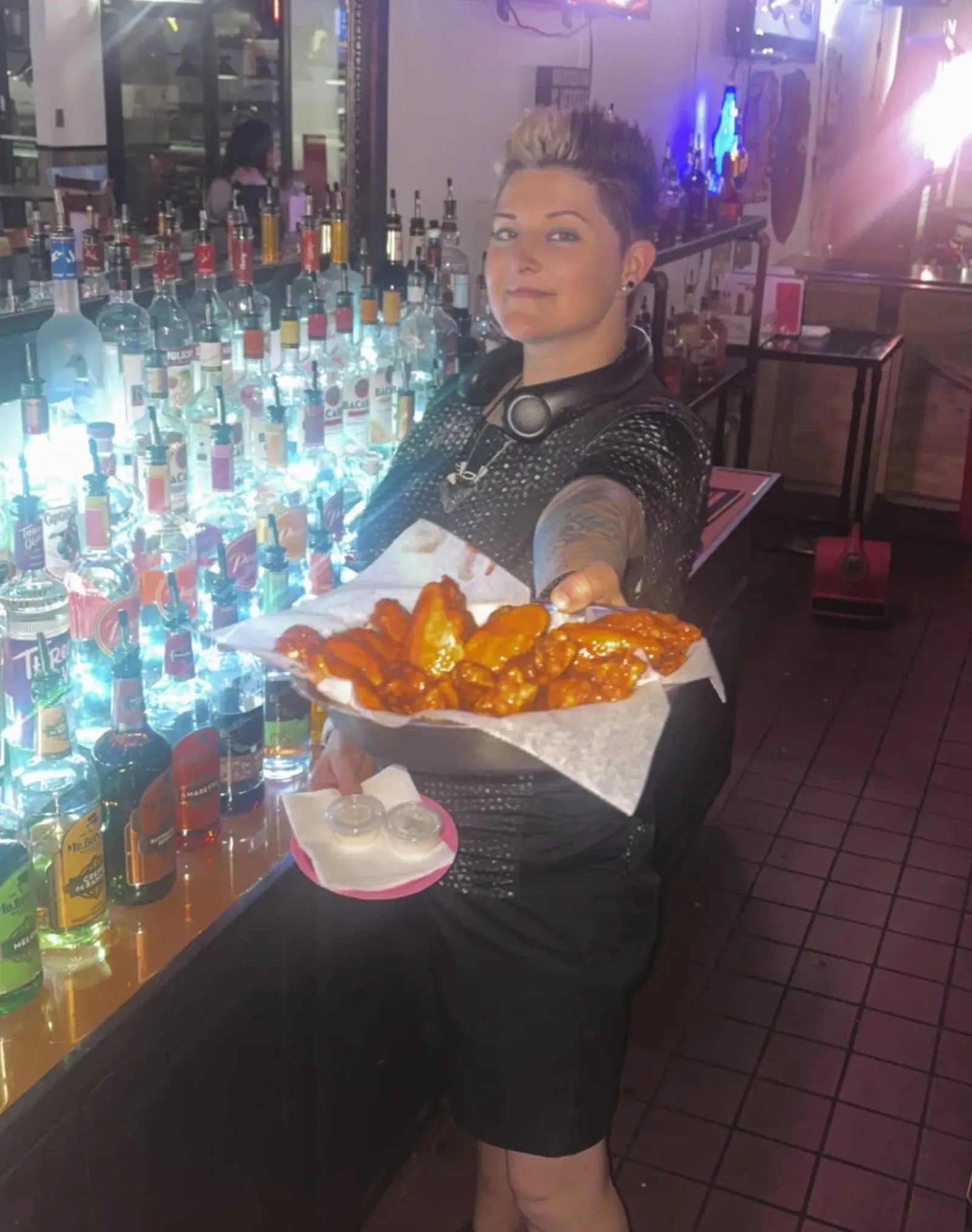 A hot order of wings being delivered to a table.