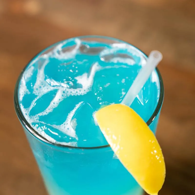 Close up of a light blue cocktail garnished with lemon