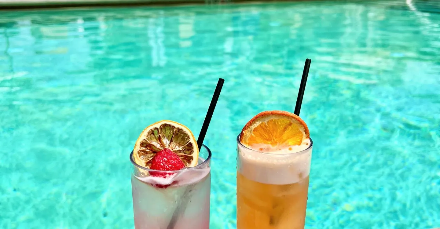 Two Drinks On A Table By A Pool