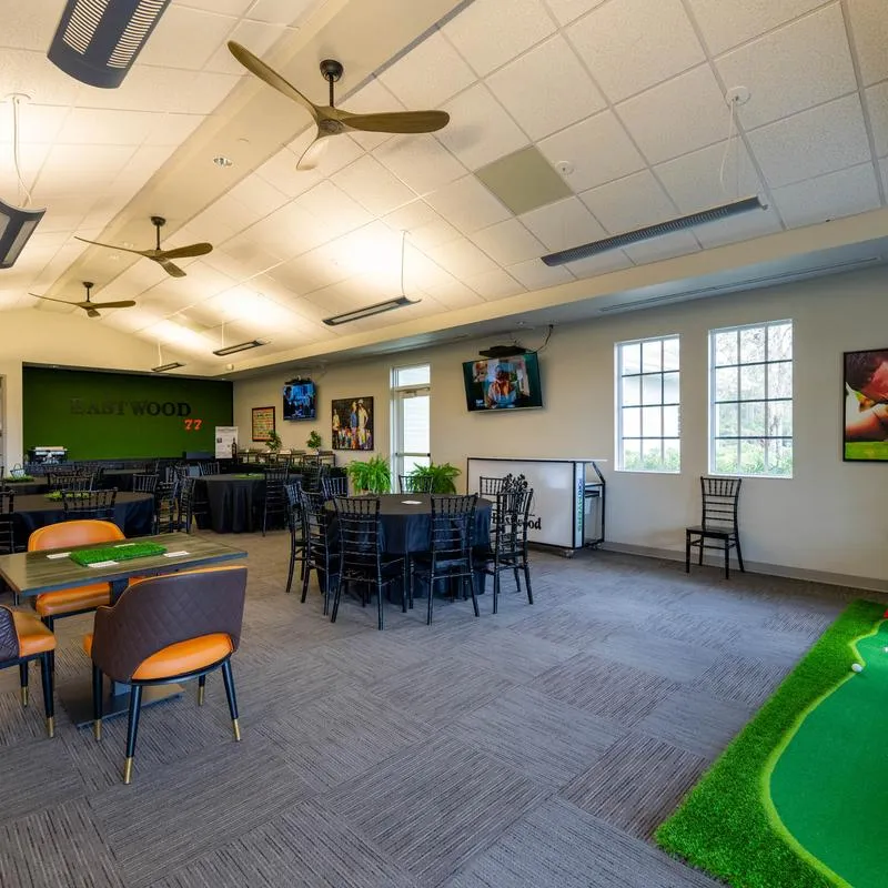 Indoor lounge featuring golf simulators and a small putting green.