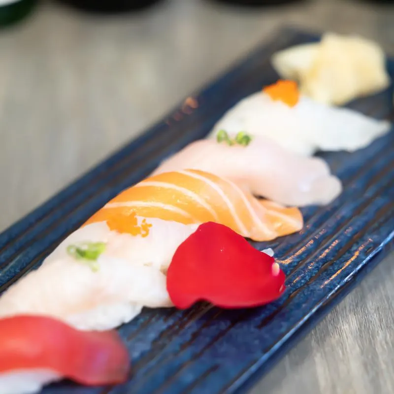 Selection of nigiri sushi garnished with a red flower petal, close-up.