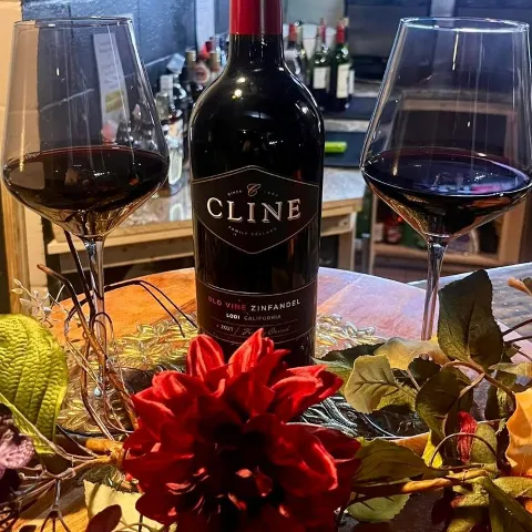 A bottle and a glass of red wine, flower arrangements.