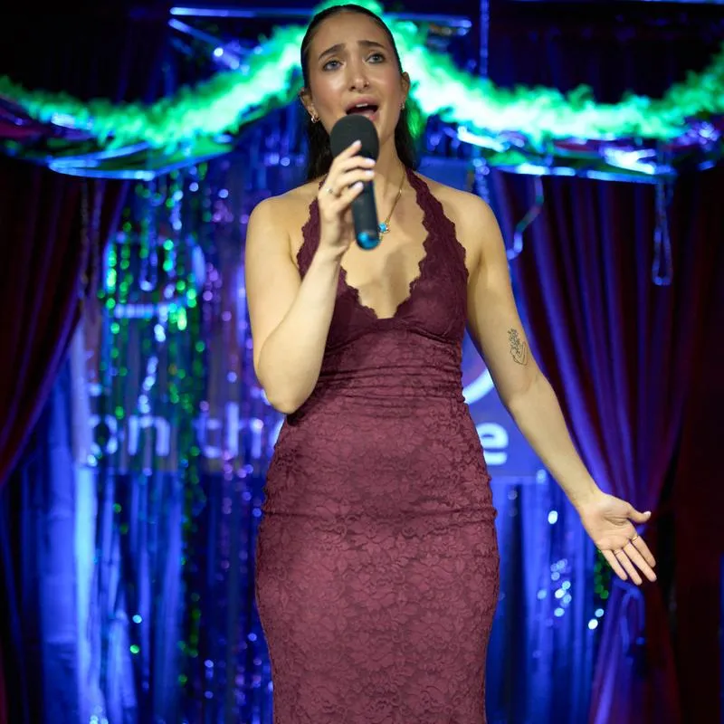 Performer singing on stage with colorful lights.
