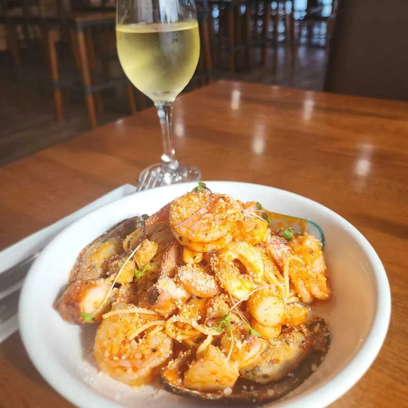 Oceans Restaurant grilled seafood paster Shrimp dish with house white wine at happy hour in Panama City Beach