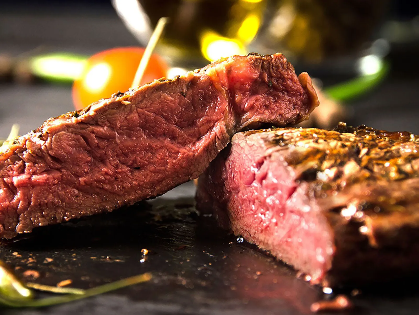 Juicy Rare steak cut in half on a black plate