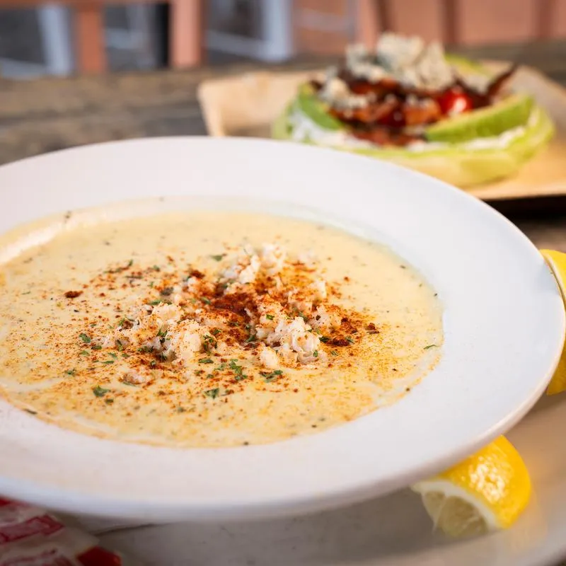 Corn Chowder, served on the table with salad in the background.