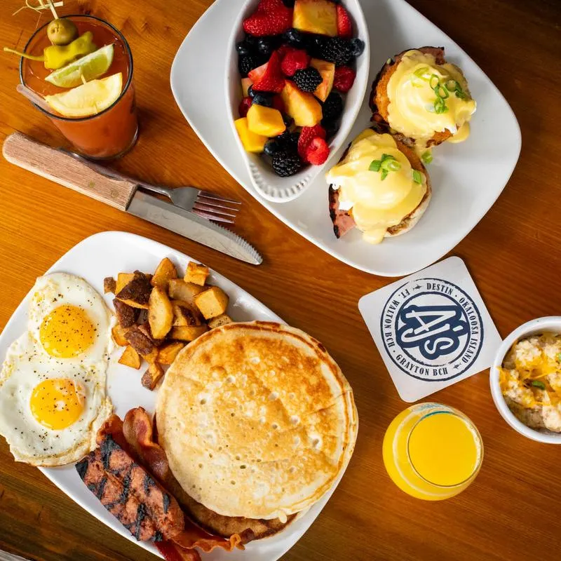 Table of Brunch food items : pancakes, fruit, Benedict, eggs.