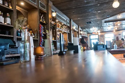 Long wooden bar with bottles, taps and warm lighting at Delany's Public House.
