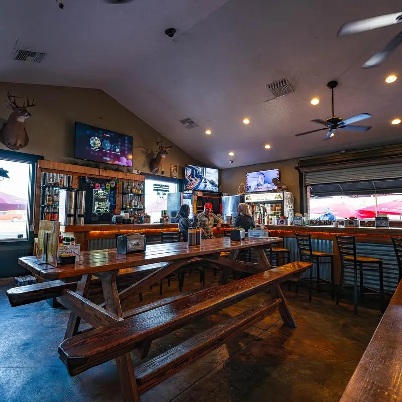 Indoor dining area with wooden tables, bar seating, and TVs.