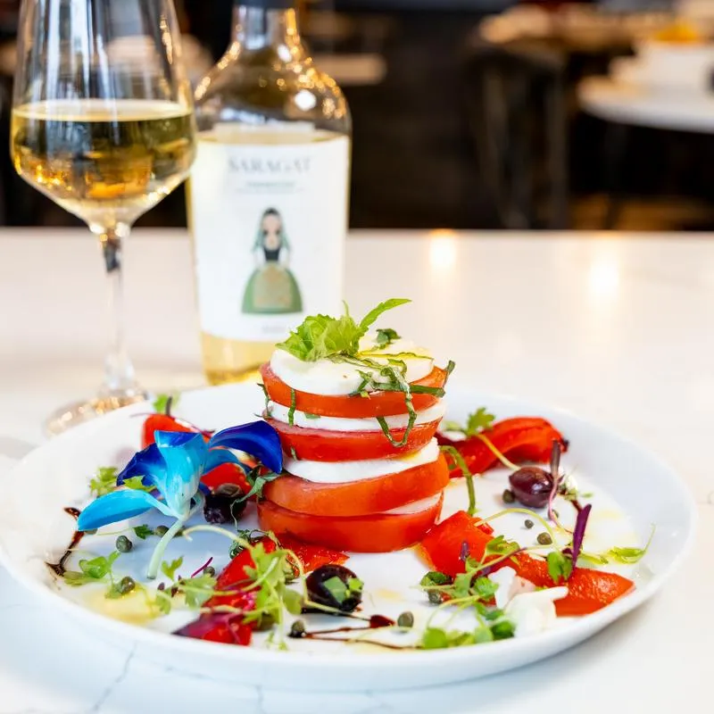Caprese salad served with a glass of rose wine.