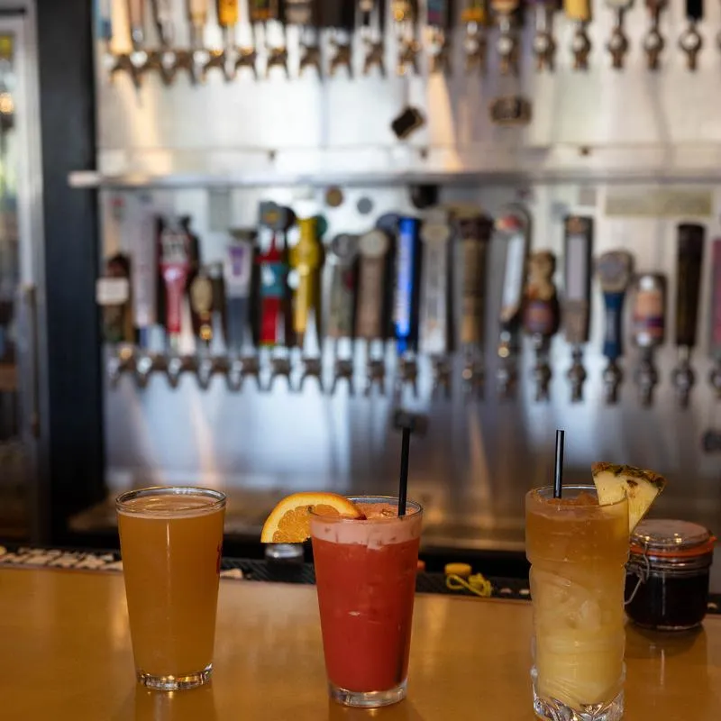 Couple of cocktails served alongside a glass of beer.