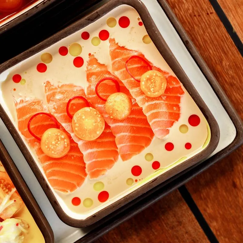 Thinly sliced, raw salmon fillets arranged in a serving plate.